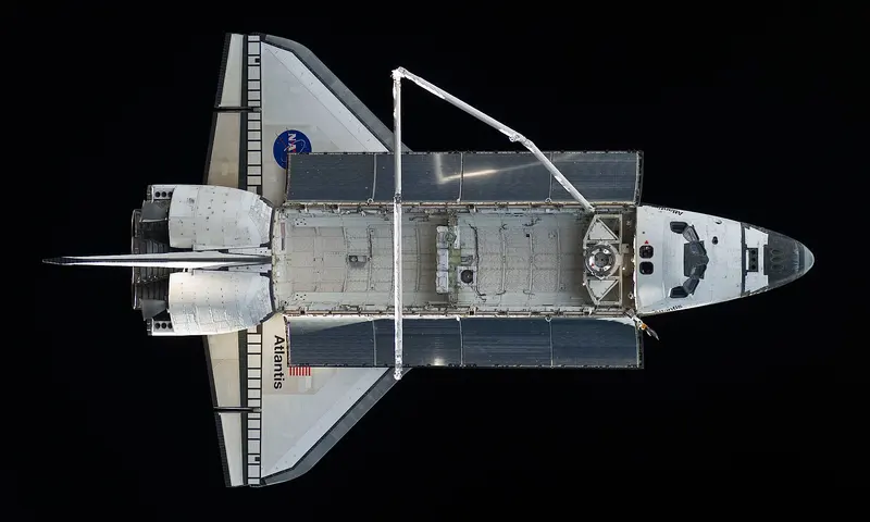A white space shuttle with its cargo doors open, seen from above against the blackness of space