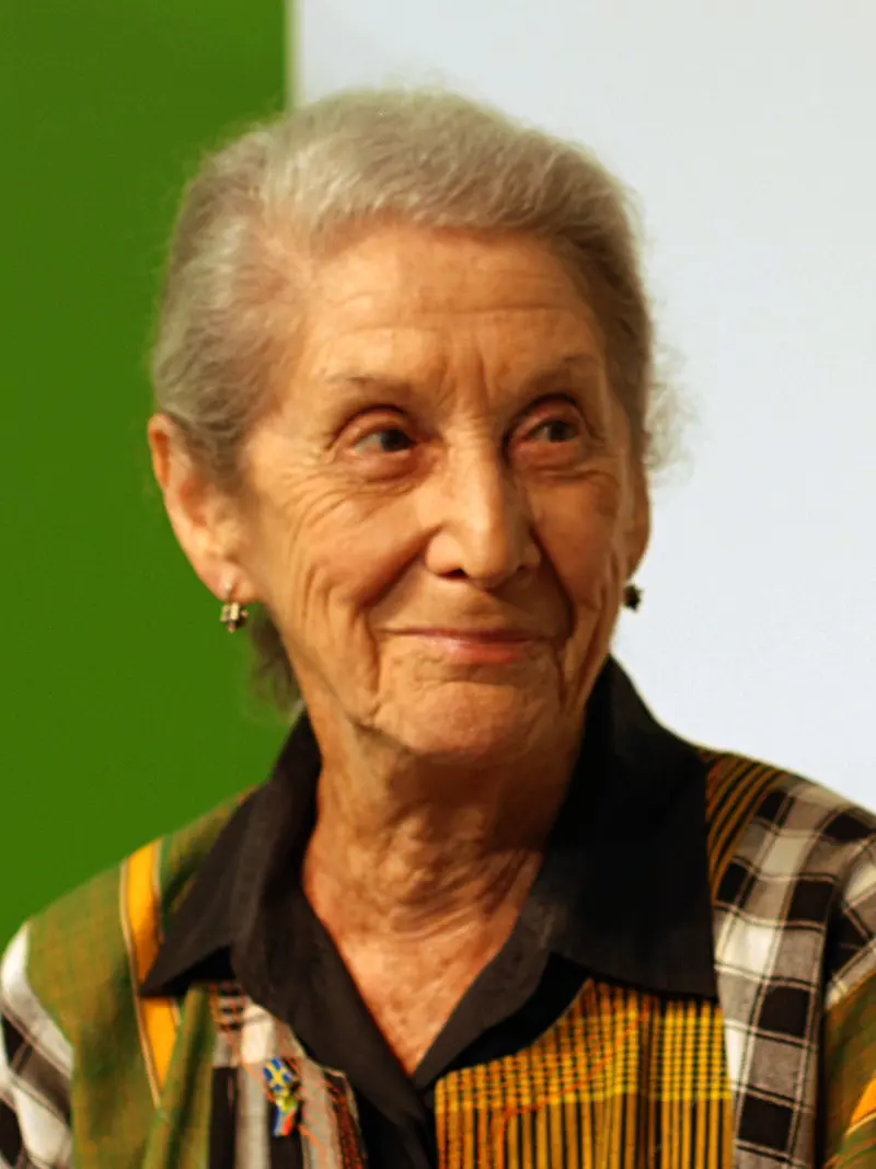 Photo of a smiling older woman with short grey hair, wearing a colourful patterned jacket