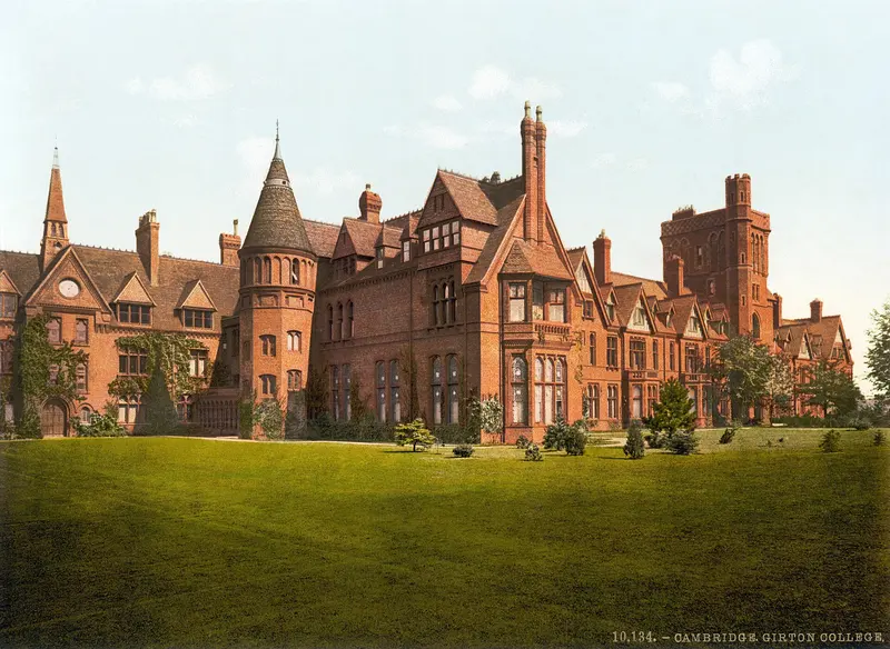 Colour picture of the red-brick buildings and towers of Girton College behind a lawn
